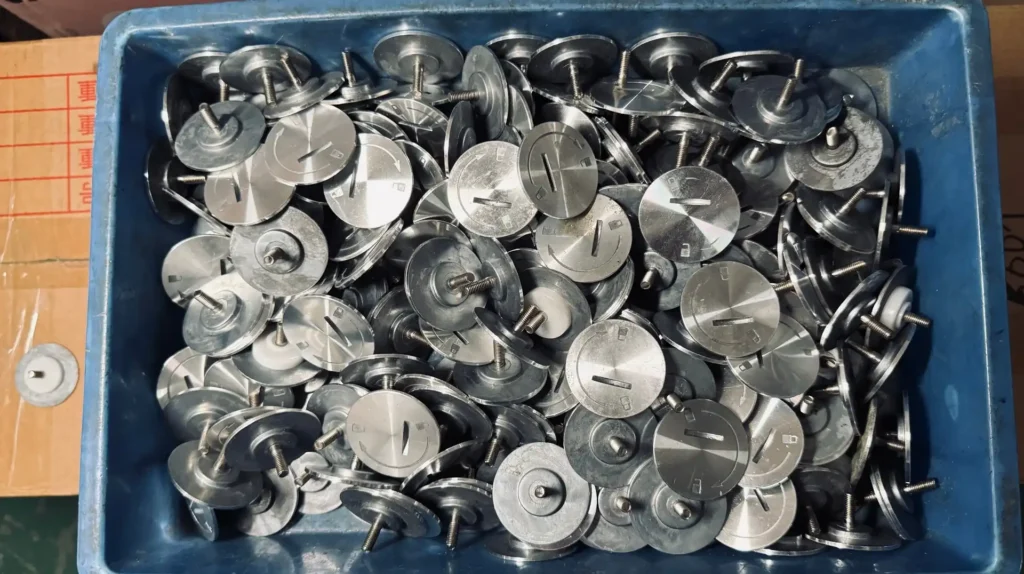 Precision-machined metal rotary knobs for commercial kitchen appliances in bulk factory storage.