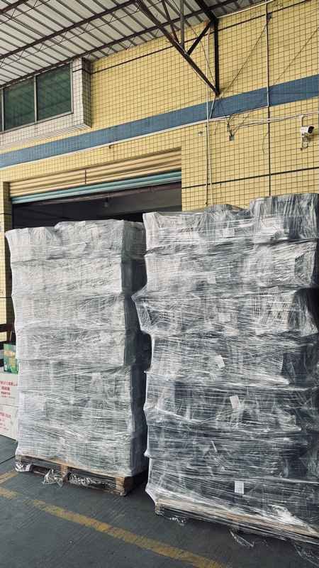 Pallets of high-density film-wrapped cardboard boxes stacked high in factory loading dock